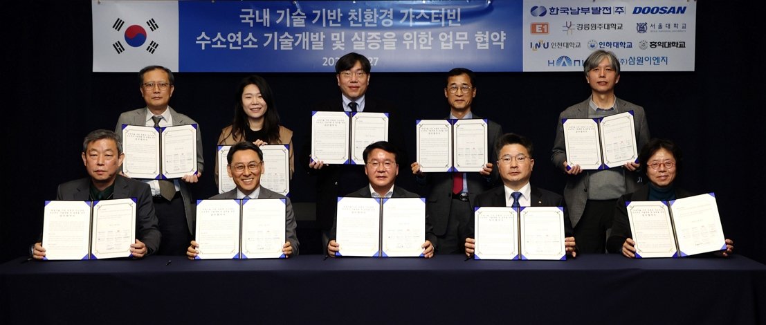 Those from the 10 parties of the local industry, academia and research sectors, including KOSPO CEO Seung Woo Lee (center of front row), Doosan Enerbility President & COO Yeonin Jung (second from the left, front row) and E1 Corporation EVP Jeong Sik Chon (fourth from the left, front row), pose for a group photo at the MoU signing ceremony held at the Bundang Doosan Tower on Jan. 27.