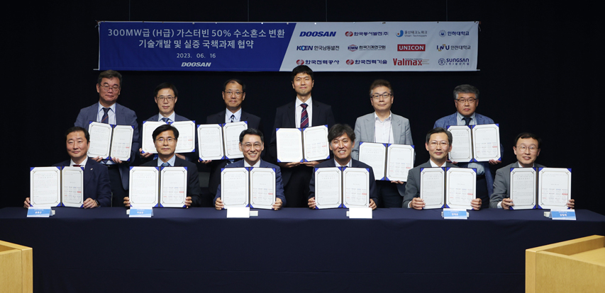 Participants pose for a group photo at the MoU signing ceremony held at the Bundang Doosan Tower on June 16th for the “National Project for Technology Development & Demonstration of 50% Hydrogen Co-fired, H-class Industrial Gas Turbine.” (Front Row, from Left to Right)  Dong Keun Song, KIMM Research Director; Sang Kyoo Lee, Executive VP of Korea South-East Power Co.; Yeonin Jung, President & COO of Doosan Enerbility; Young-moon Kim, President & CEO of Korea East-West Power Co.; Tae Kyun Kim, KEPCO Technology Innovation Director; Il-Bae Kim, Executive VP of KEPCO E&C. (Back Row, From Left to Right)  Kwangmin Kim, President of Unicon System;  Hanwoo Lee, Energy Technology Director of Ulsan Technopark; Dongsup Kim, Professor of Inha University; Minchul Lee, Professor of Incheon National University; Dongyeol Park, CEO of Valmax Co.; Sangkyu Seo, Executive VP of Sungsan Co.